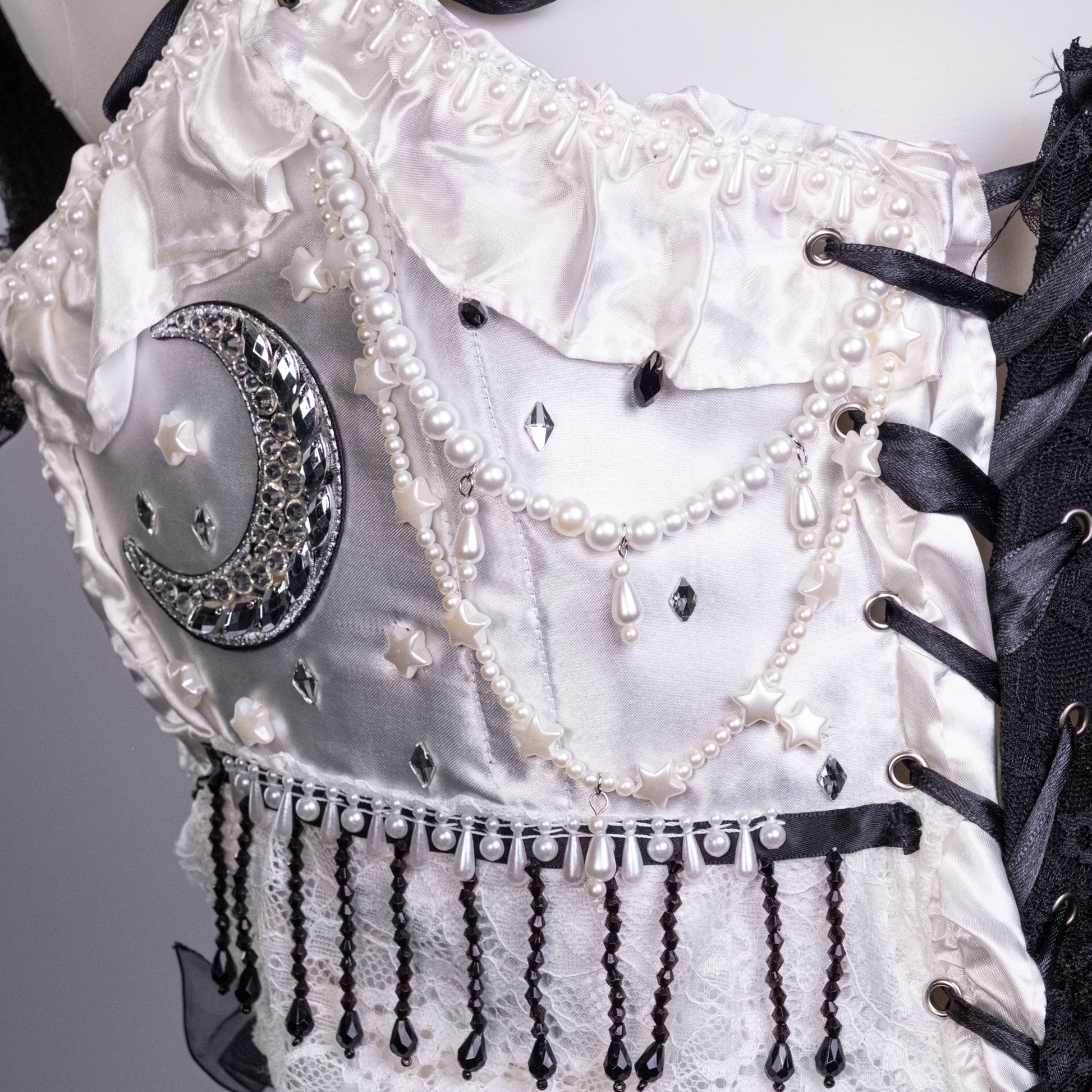 Détail du corset Pierrot blanc orné de perles, strass et médaillon